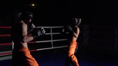 Adam kask ve boks eldivenleri karanlıkta ringde yenerek bir kızla. Ağır çekim
