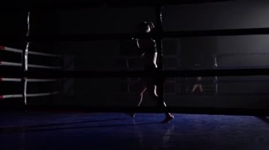 Kız atlet trenler karanlık ringde bacaklarını atıyor. Siluet. Ağır çekim