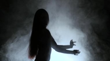 Kız seksi bir dans duman içinde dans ediyor. Siyah arka plan. Siluet