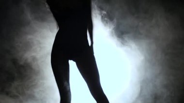 Kadın seksi bir dans duman içinde dans ediyor. Siyah arka plan. Siluet