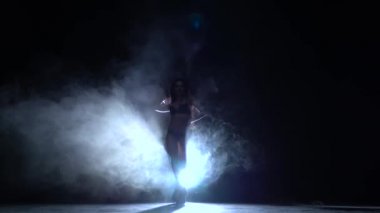 Kız erotik hareketleri dans ediyor. Siyah duman arka plan. Siluet