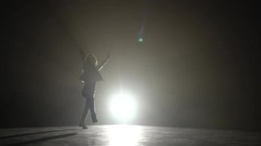 Küçük çocuk bir hareketten stüdyoda yok. Siyah duman arka plan. Siluet. Arkadan ışık