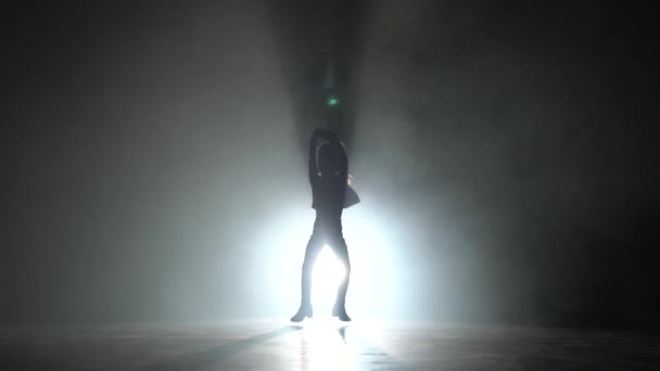 Bebé bailando en un estudio oscuro. Fondo de humo negro. Silueta. Luz por detrás — Vídeos de Stock