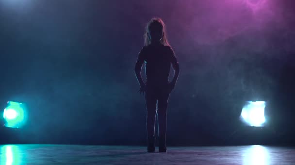 Child girl sit on the twine in the studio. Multicolor smoke background. Silhouette. Light from behind — Stock Video