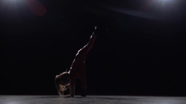 Lilla barnet gör en handstand i studion. Svart bakgrund. Slow motion — Stockvideo