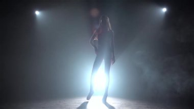 Modeli bir mayo podyumda gösterir. Ağır çekim. Siluet. Siyah duman arka plan