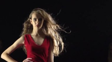 Kızlar kırmızı kıyafetlerle poz. Siyah arka plan. Ağır çekim