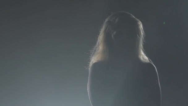 Modell egy sötét stúdióban pózol. Lassú mozgás. Sziluettjét. Fekete füst háttér — Stock videók