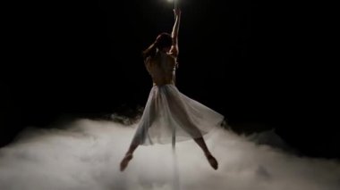 Kadın yakınındaki duman içinde dans pole erotik dans ediyor. Siyah duman arka plan. Ağır çekim