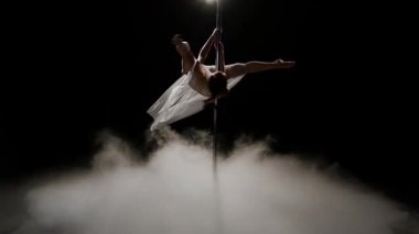 Striptizci kutup dans karanlık stüdyosu yapıyor. Siyah duman arka plan. Ağır çekim