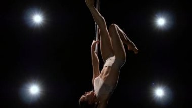 Spor hileler kutup striptizci tarafından gerçekleştirilir. Siyah arka plan. Ağır çekim.