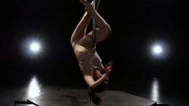 Striptiz kutup stüdyoda iplik. Siyah arka plan. Ağır çekim. Fener ışığı