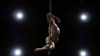 Spor hileler kutup striptizci tarafından gerçekleştirilir. Siyah arka plan. Ağır çekim.