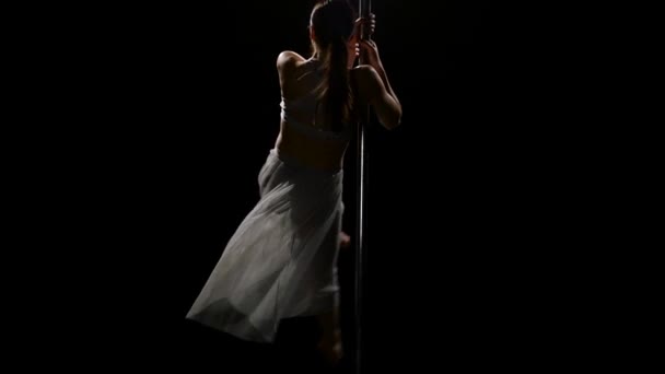 Bailarina femenina realiza poledance sexy en polo. Fondo negro. Movimiento lento — Vídeos de Stock