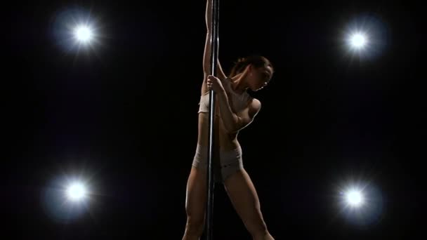 Erotische dansen op een pylon uit een meisje danser. Zwarte achtergrond. Slow motion. — Stockvideo