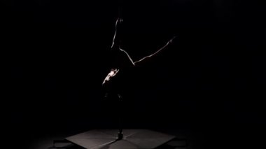 Pole akrobatik hareket. Siyah arka plan. Ağır çekim. Siluet