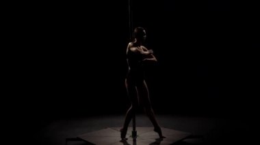 Dansçı poledance kutup dans gece kulübünde gerçekleştirir. Siyah arka plan. Ağır çekim. Siluet