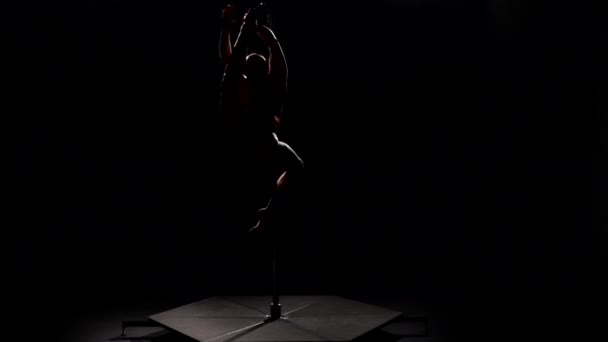 Une fille danse sur un pylône. Fond noir. Au ralenti. Silhouette — Video