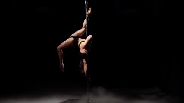 Girl with sexy shape is dancing near the pole . Black smoke background. Slow motion — Stock Video