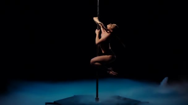 Bailarina de striptease en humo azul en un poste. Fondo de humo negro. Movimiento lento — Vídeo de stock