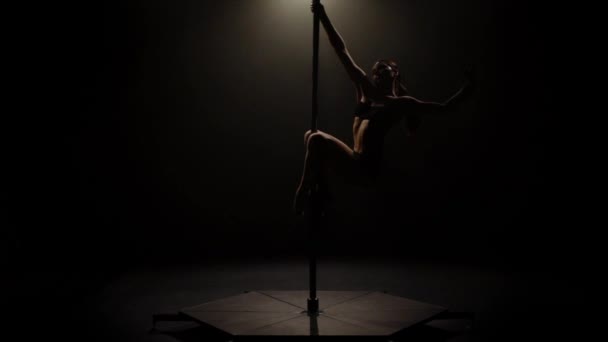 Female dancer sexy poledance . Black background. Slow motion. Silhouette — Stock Video