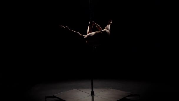 Il movimento acrobatico sul palo è eseguito da una ragazza. Fondo nero. Al rallentatore. . Silhouette — Video Stock