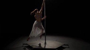 Kadın dansçı seksi poledance gerçekleştirir. Siyah arka plan