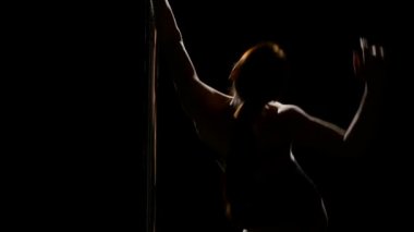 Kadın dansçı seksi poledance gerçekleştirir. Siyah arka plan. Yakın çekim