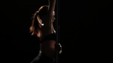 Kız dans adımları pilon üzerinde gerçekleştirir. Siyah duman arka plan. Yakın çekim