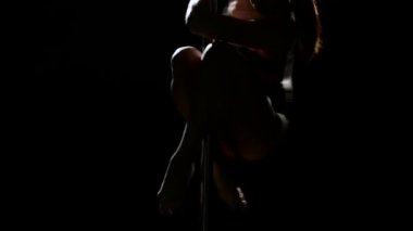 Şekil kadınla kutup dans ediyor. Siyah arka plan. Siluet. Yakın çekim