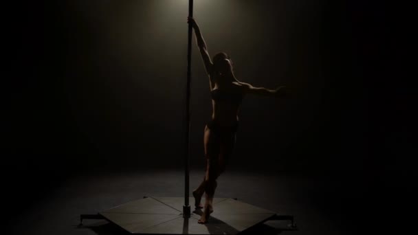 Dívka tančí tanec na pylon. Černé pozadí. Silueta — Stock video