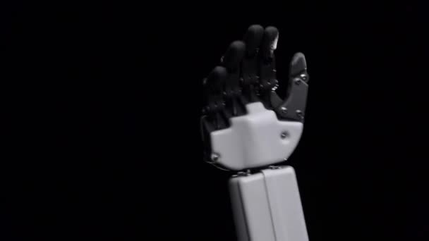 Hand van een robot close-up hallo zwaaien. Zwarte achtergrond — Stockvideo