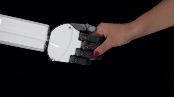 Hand eines Roboters und Hand eines Mädchens in einem Händedruck. schwarzer Hintergrund. Nahaufnahme — Stockvideo