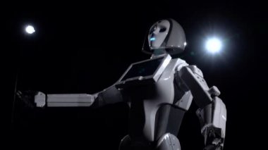 Robot konuşuyor ve çeşitli hareketleri tekrarlar. Siyah arka plan