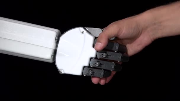 Hand of a robot and a mans hand in one handshake. Black background. Close up — Stock Video