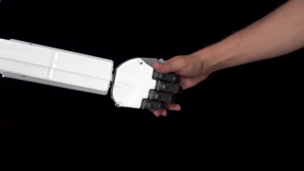 Hand av en robot och en mans hand i ett handslag. Svart bakgrund. Närbild — Stockvideo