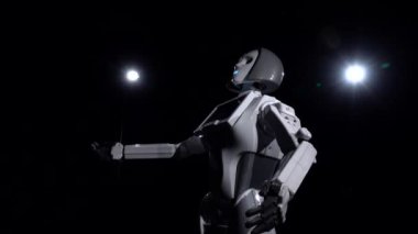 Robot elleriyle işaret hareketler yapar. Siyah arka plan