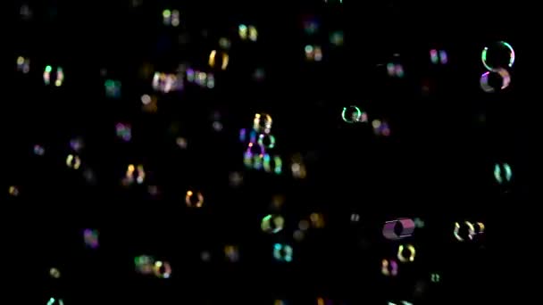 Různé velikosti a barvy mýdlové bubliny létat. Černé pozadí — Stock video