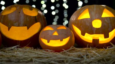 Yanan ürkütücü yüzü olan üç halloween balkabağı. Siyah bokeh arka plan. Yakın çekim