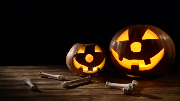 Страшный вырезал на Хэллоуин две тыквы и кости. Чёрный фон — стоковое видео