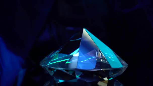 Un diamant tourne et brille dans les couleurs bleues 