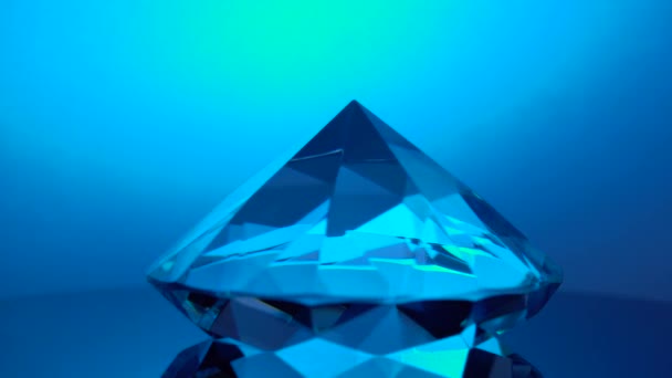 Diamond rotating at its point reflects blue light — Stock Video