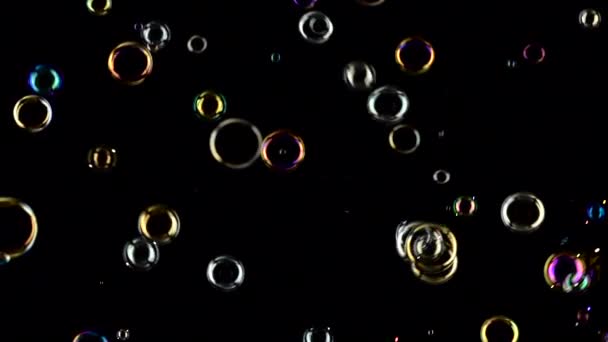 Мильні бульбашки літають і лопаються в повітрі. Повільний рух. Чорний фон — стокове відео
