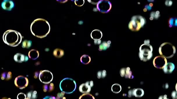 Las burbujas de jabón vuelan y estallan en el aire. En cámara lenta. Fondos negros — Vídeo de stock
