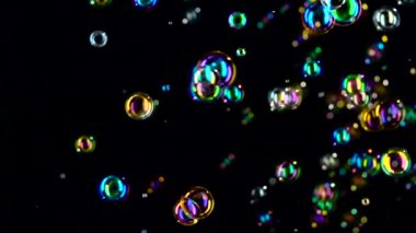 Sabun köpüğü sinek ve farklı renklerde fade. Ağır çekim. Siyah arka plan