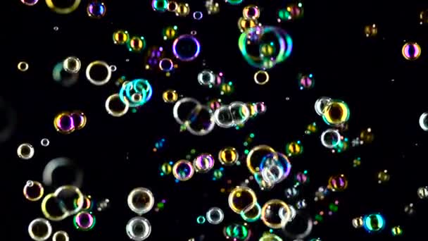 Las burbujas de jabón vuelan y se desvanecen en diferentes colores. En cámara lenta. Fondo negro — Vídeo de stock