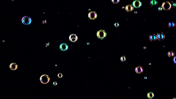 Різні розміри і кольорові мильні бульбашки літають. Повільний рух. Чорний фон — стокове відео