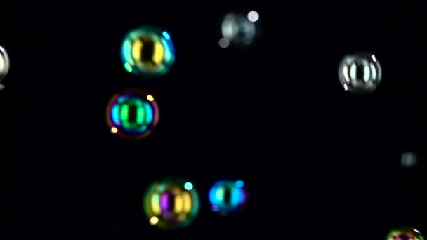 Las burbujas de jabón de diferentes tamaños y colores vuelan de cerca. En cámara lenta. Fondos negros — Vídeos de Stock