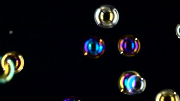 Différentes bulles de savon de taille et de couleur volent de près. Au ralenti. milieux noirs — Video