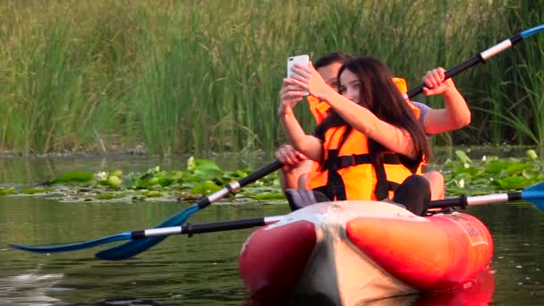 O tipo e a rapariga estão sentados num caiaque e fazem selfie. Movimento lento — Vídeo de Stock